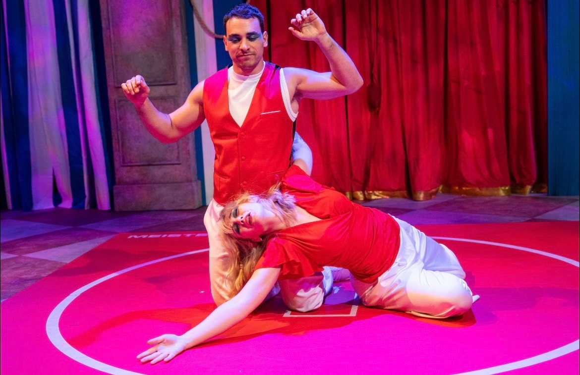 Lex Leone on stage kneeling on pink floor with co-star