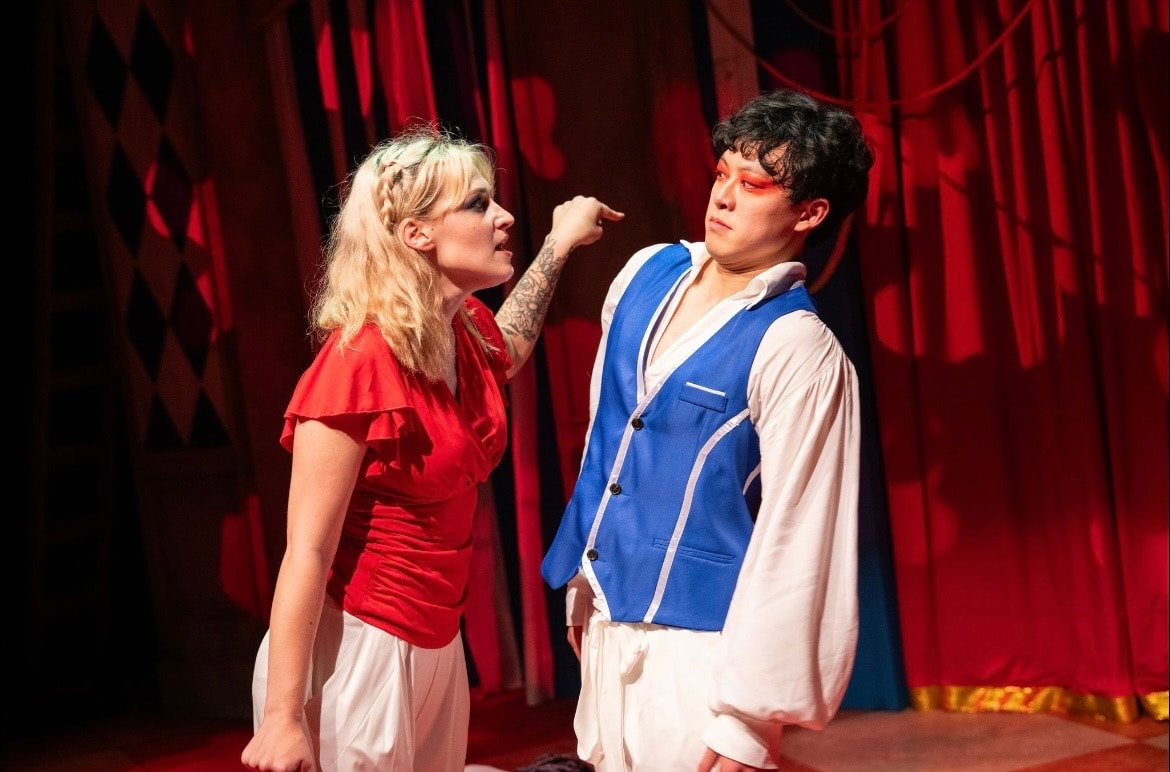 Lex Leone on stage in red top pointing at co-star