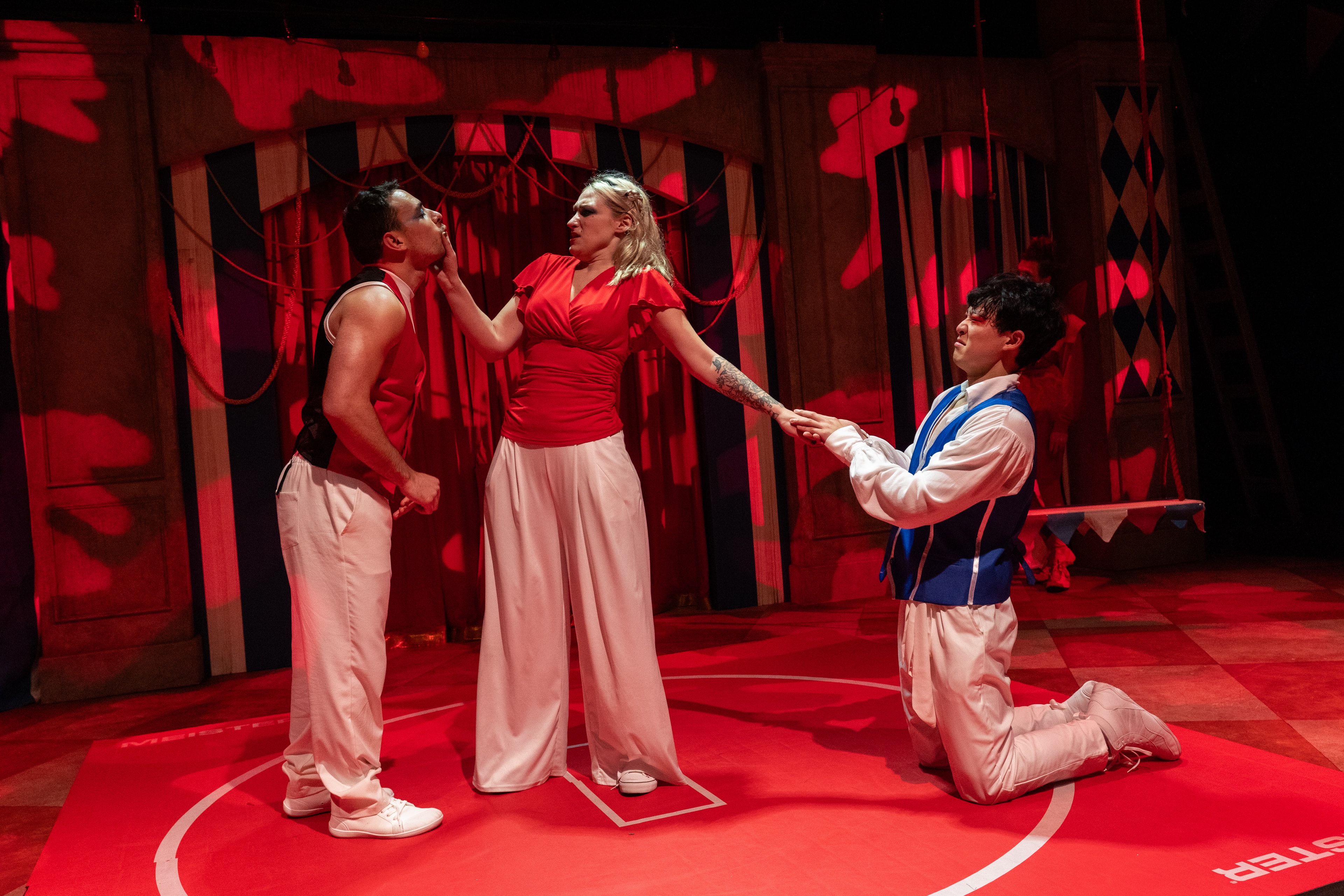 Lex Leone on stage in red top between two co-stars